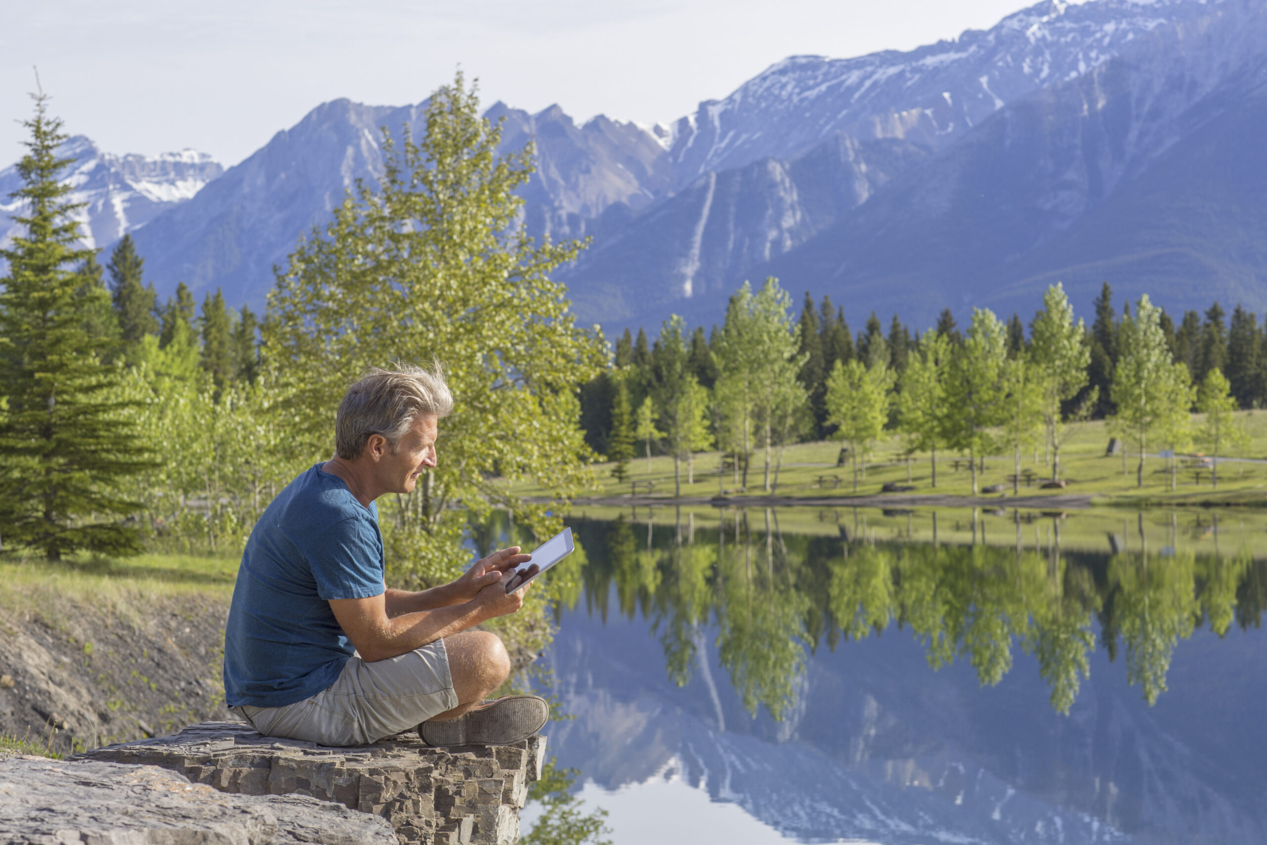 Man relaxes near forested lake in the morning